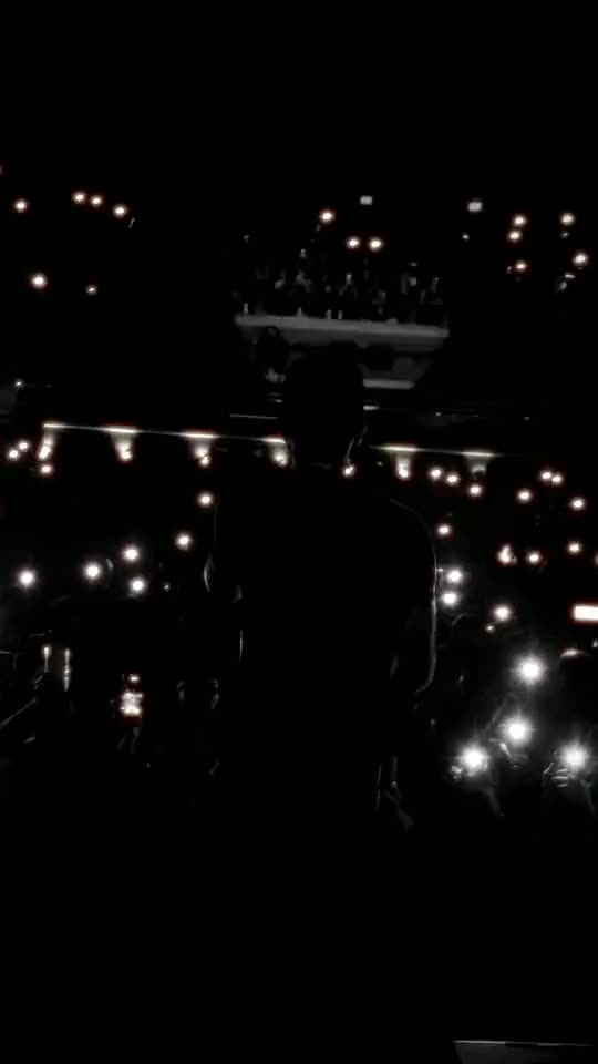 Live show: the artist on stage facing a crowd lit by phones